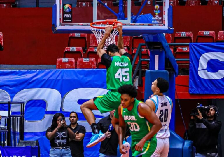 Jogador brasileiro em enterrada enquanto é observado por atleta uruguaio.