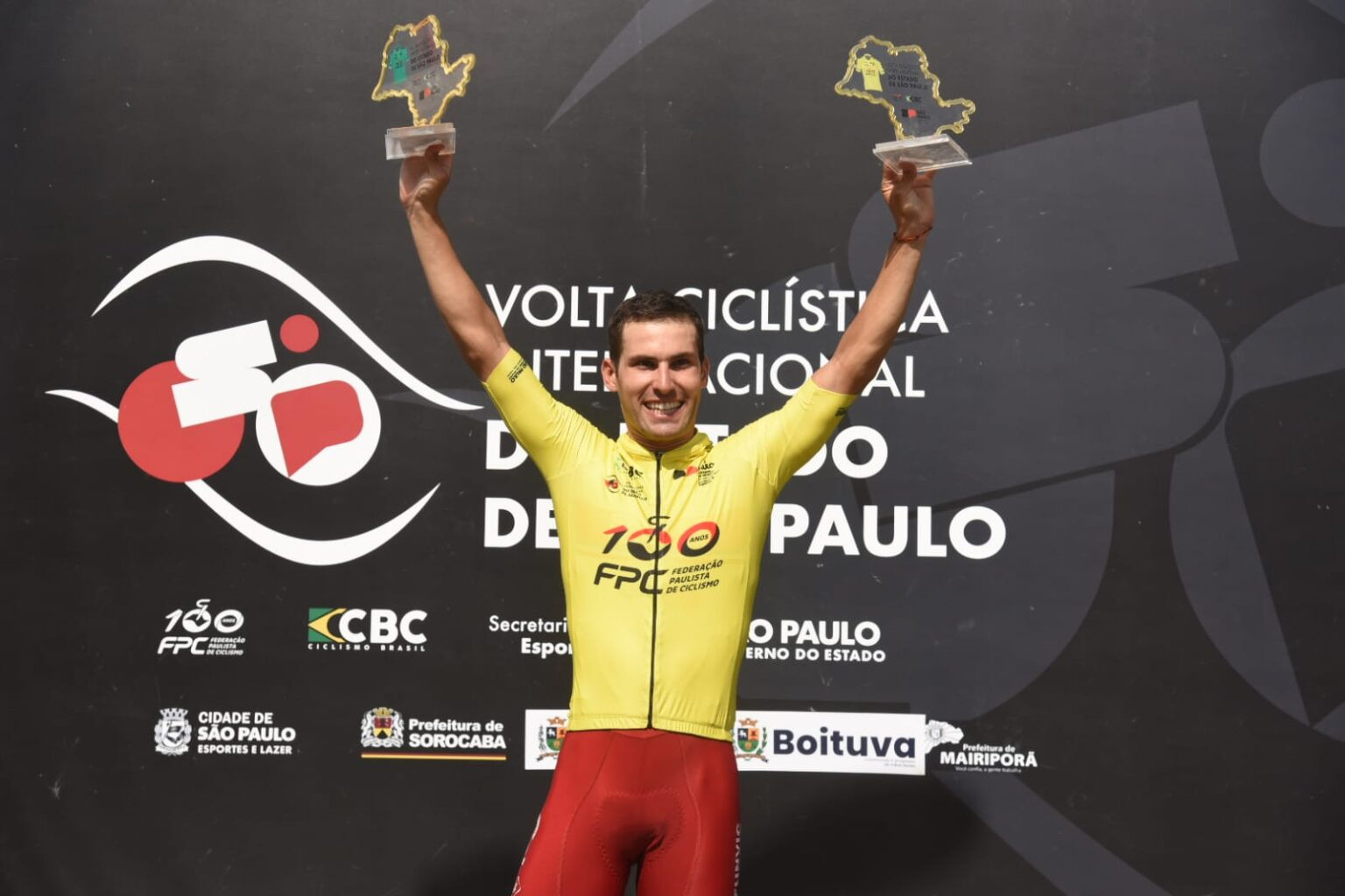 Igor Molina ergue os braços com troféus no pódio