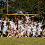 Equipe brasileira posa para foto no campo com a trave ao fundo