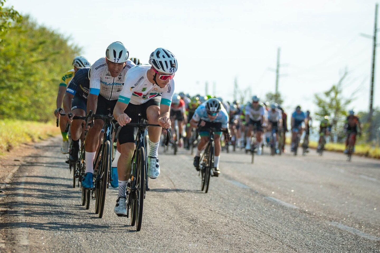 Ciclistas enfileirados em estrada.